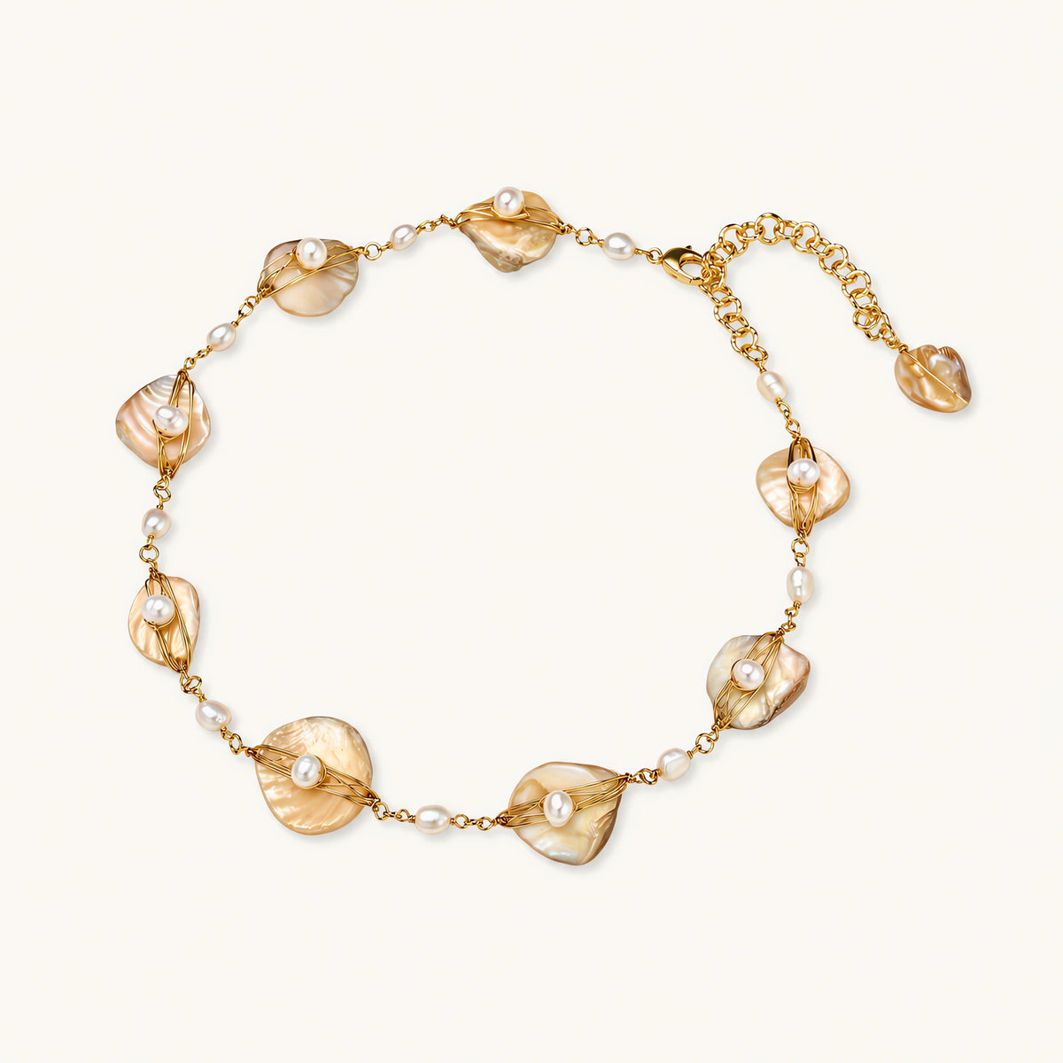 Gold-plated necklace with wire-wrapped shell pieces and freshwater pearls on neutral background, adjustable chain visible.
