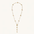 Gold-plated lariat necklace with baroque pearls and textured caps on cream background, showing adjustable Y-shaped design.
